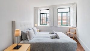 A bedroom with a bed, bedside table, lamp, and a chair. - Invictus Hostel (Porto)