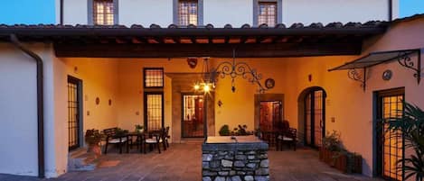 A building with a patio area, stone columns, and a covered seating area.