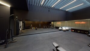Een moderne sportschool met trainingsapparatuur, een bank en een muur met een neonbord.