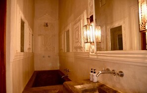 A bathroom with a bathtub, a sink, and wall sconces. - Olepangi Farm (Nanyuki)