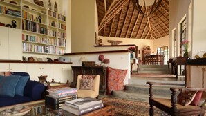 Un salón acogedor con techo alto, chimenea y una escalera que sube a otro nivel.