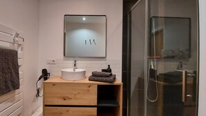 A modern bathroom with a white sink, a mirror above it, and a towel hanging on a rack. There is a wooden vanity with drawers and a small shelf. - O Tour's Angels "Rabelais" (37000 TOURS)