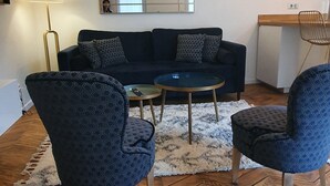 A modern living room with a dark blue sofa, patterned armchairs, a coffee table, and a herringbone wooden floor. - O Tour's Angels "Rabelais" (37000 TOURS)