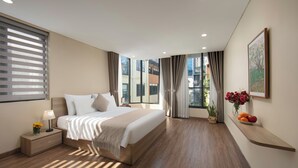 Een moderne hotelkamer met een groot bed, nachtkastje en een raam met gordijnen.