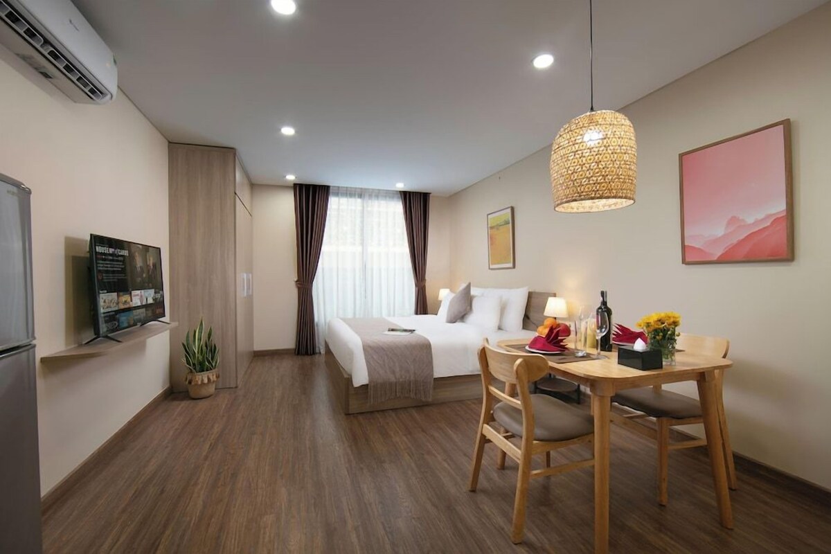 Une chambre d’hôtel comprenant un lit, une table de chevet, une lampe et un coin repas avec une table et des chaises.