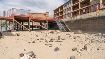 Un hôtel situé en bord de mer, doté d’une terrasse en bois, d’un escalier et d’un mur de soutènement en béton.