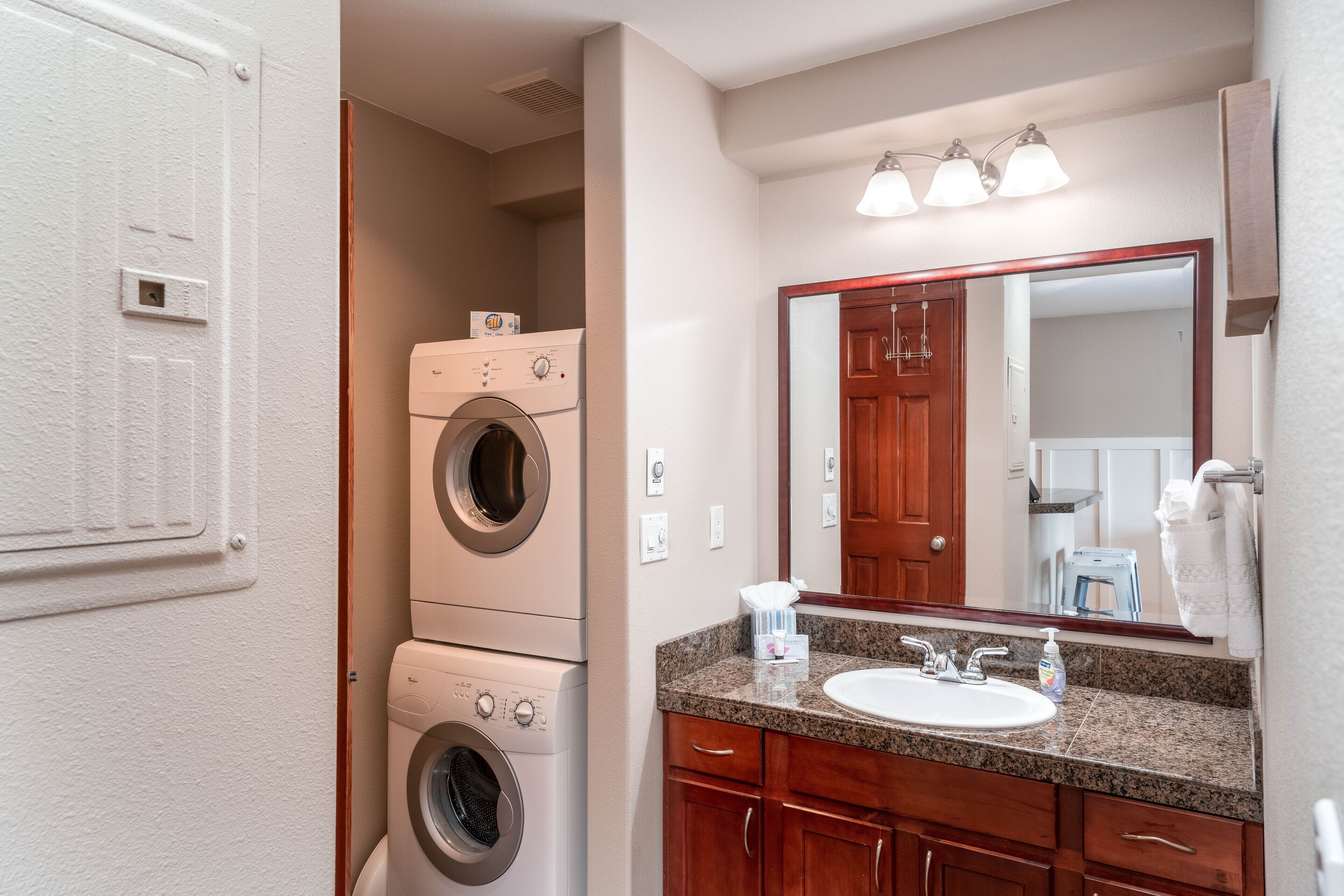 A compact bathroom with a built-in washer and dryer, a sink, and a mirror.