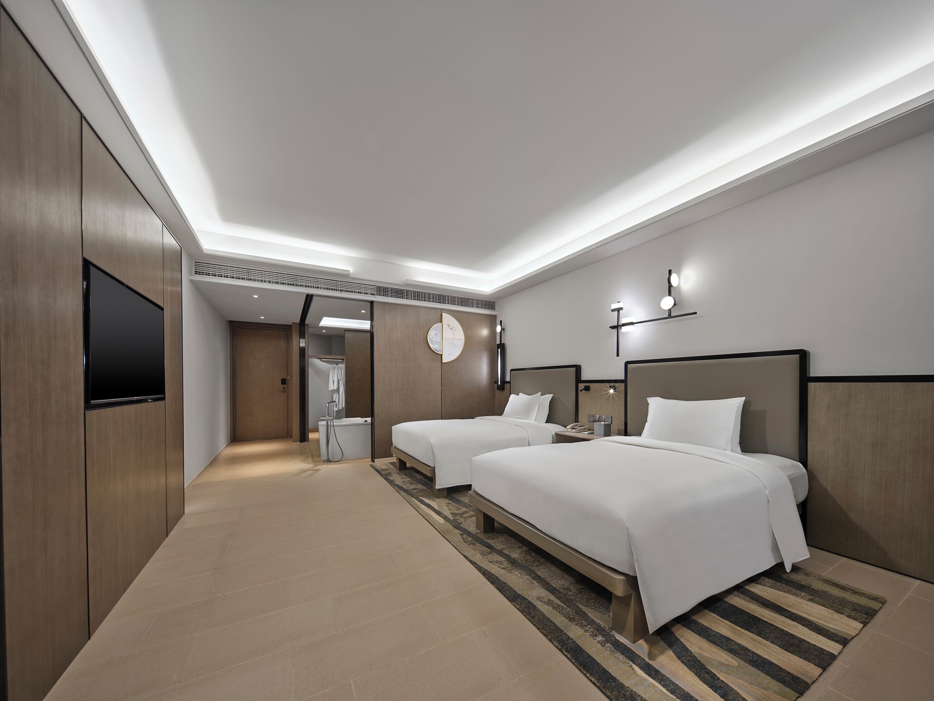 A modern hotel room with two beds, a flat-screen TV, a shower, and a walk-in closet.