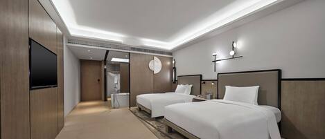 A modern hotel room with two beds, a flat-screen TV, a shower, and a walk-in closet.