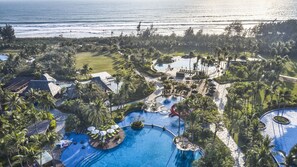 Un resort con un amplio área de piscina, palmeras y vistas al océano.