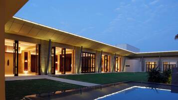 A modern hotel with a swimming pool, covered outdoor area, and well-lit entrance.