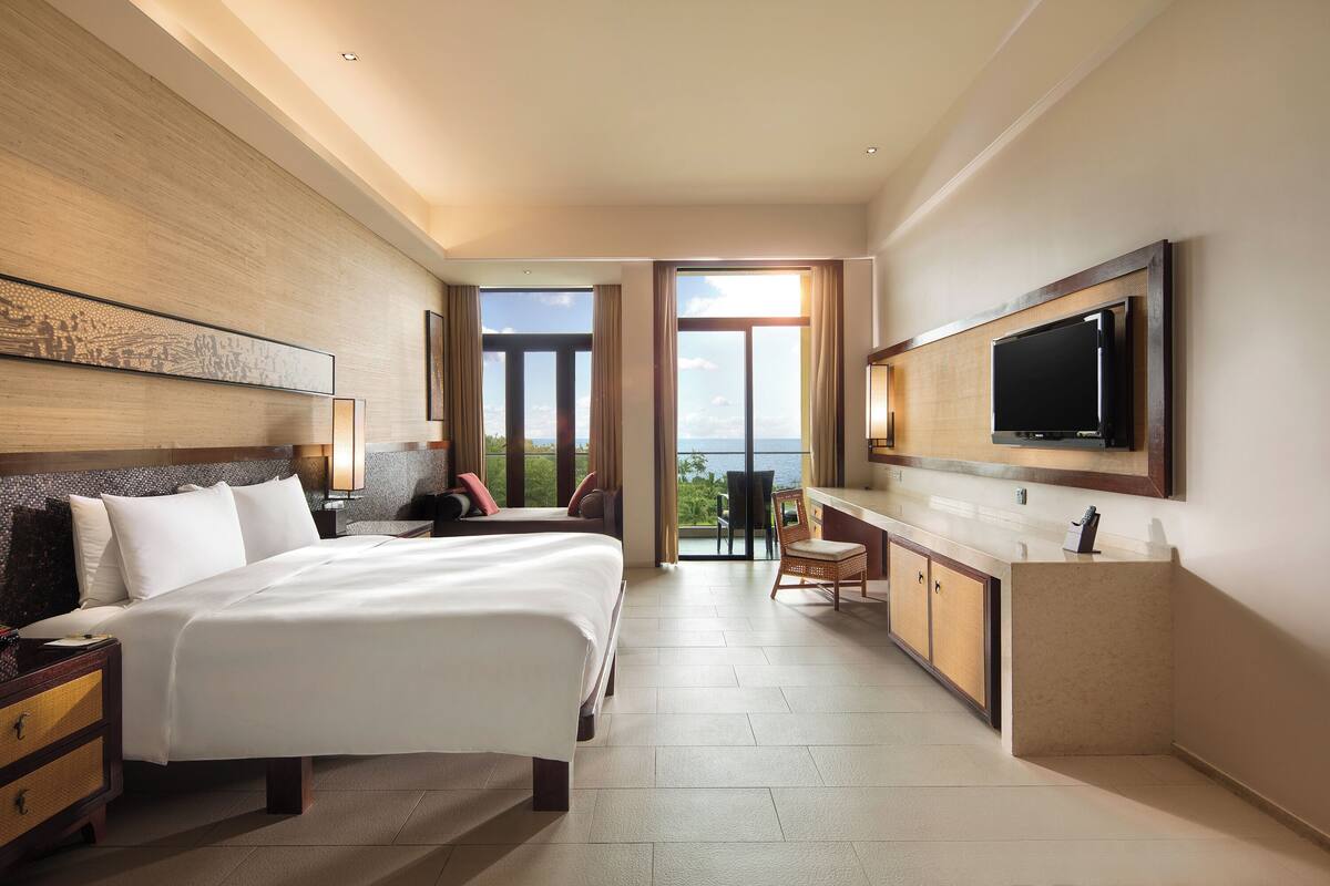 Une chambre d’hôtel moderne, dotée d’un grand lit, d’un bureau et d’une télévision.