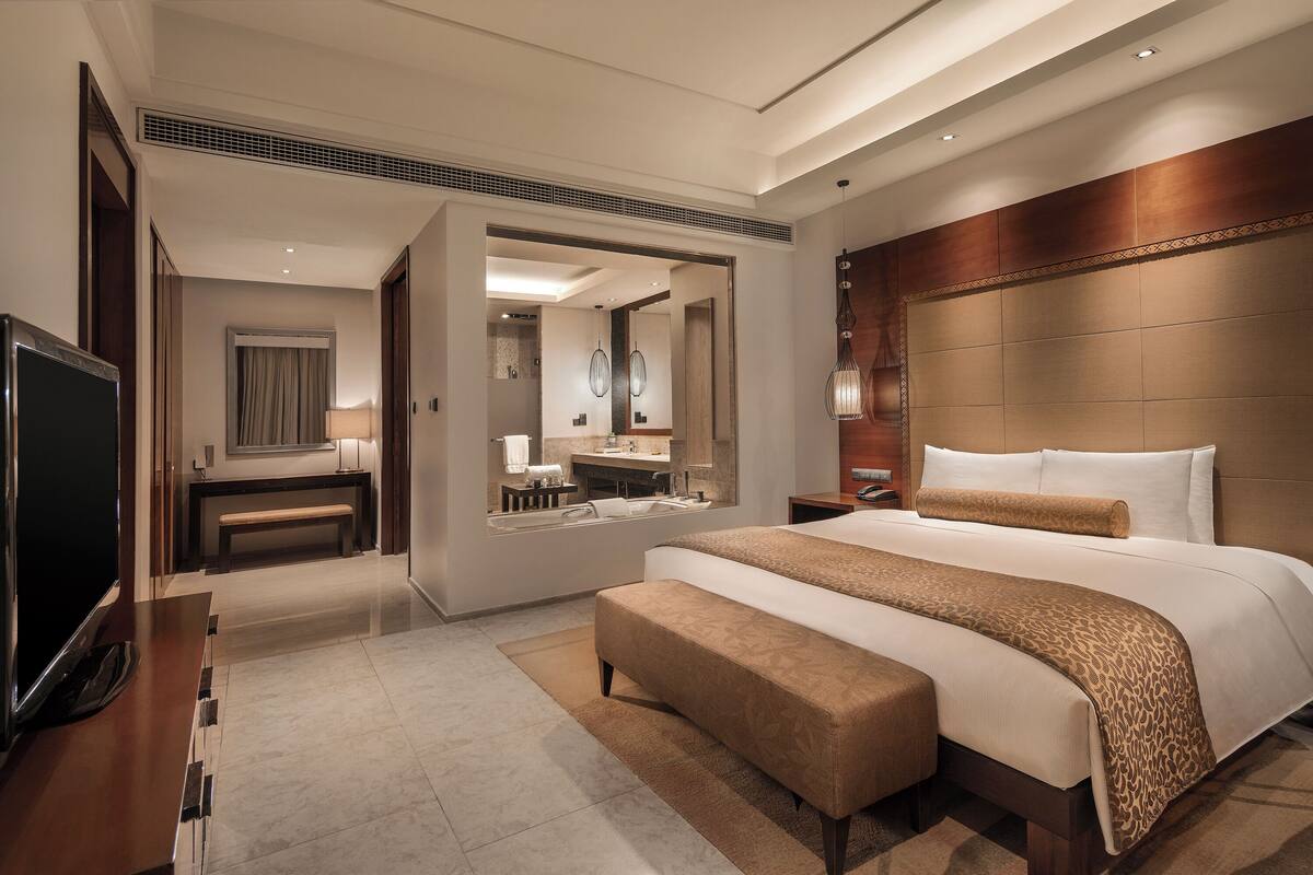 Une chambre d’hôtel moderne dotée d’un grand lit, d’une télévision, d’une salle de bain et d’un coin salon.