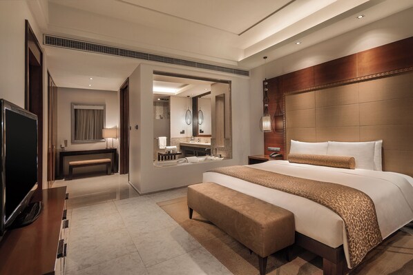 Una habitación de hotel moderna con una cama grande, un televisor, un baño y una zona de estar.
