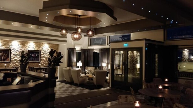 Een hotellobby met een zwart-wit geruite vloer, zithoeken en een receptiebalie.