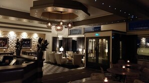 A hotel lobby with a checkered floor, seating areas, and a reception desk.