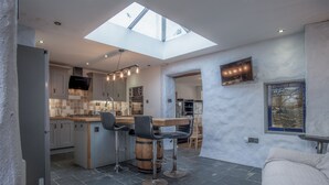 A modern kitchen with a skylight, bar stools, and a dining area. - Cambrian Cottage - 3 Bed Cottage - Tenby (Tenby)