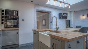 A kitchen with a double sink, stainless steel appliances, and a wooden countertop. - Cambrian Cottage - 3 Bed Cottage - Tenby (Tenby)