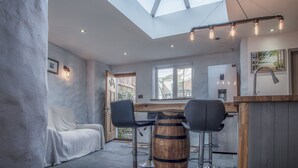 A modern interior with a skylight, a wooden bar counter, and a white sofa. - Cambrian Cottage - 3 Bed Cottage - Tenby (Tenby)
