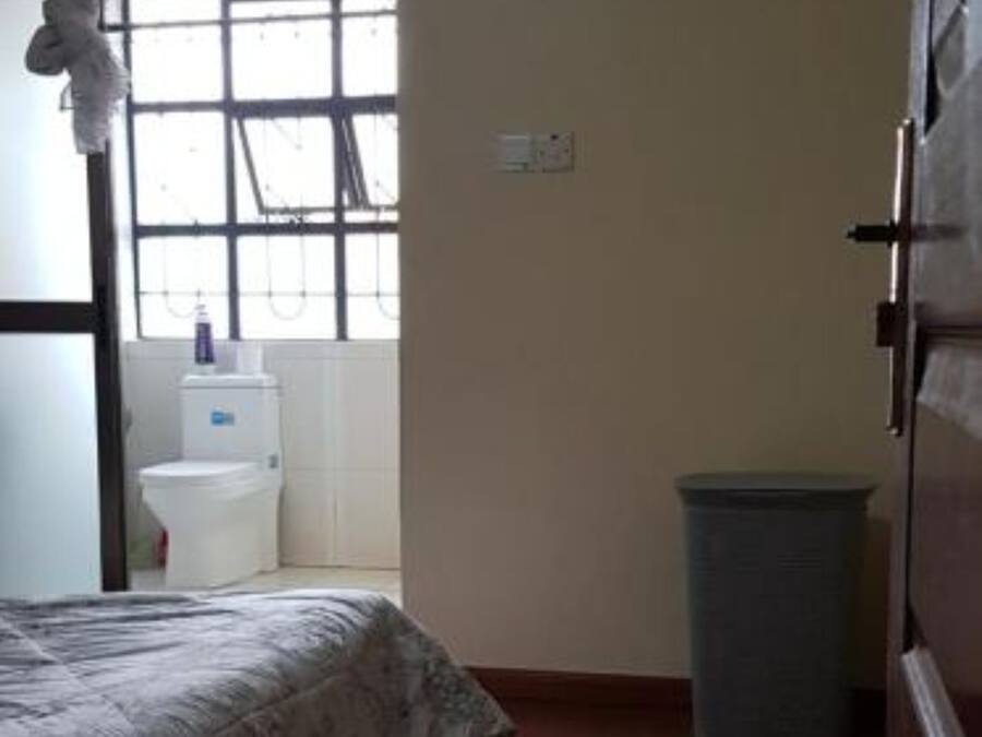 Un dormitorio con cama, ventana, cubo de basura y armario.