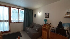 Une petite pièce agréable, avec un canapé, un meuble en bois et un bureau.