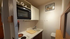 Une cuisine de taille réduite, équipée d’un four à micro-ondes, d’un évier et d’un petit plan de travail.