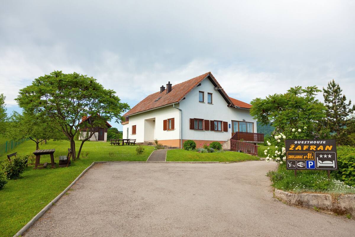Ein Gästehaus namens Zafran mit einem Schotterweg, der zu einem weißen Gebäude mit rotem Dach führt.