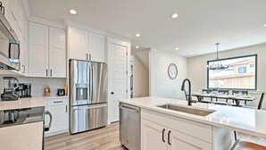 Una cocina moderna con armarios blancos, electrodomésticos de acero inoxidable y una isla grande con un lavamanos.