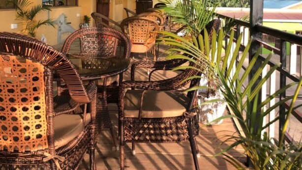 A covered outdoor seating area with wicker furniture and potted plants. - Broad Park Hotel (Mbale)