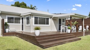 A two-story house with a covered patio area, a front door, and a small front yard. - Berrara Beach House - Belle Escapes Jervis Bay (Berrara)