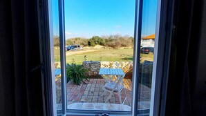 A view through a glass door leading to an outdoor patio area with a brick floor, a wooden table, and chairs. - Holiday house on peaceful location in the suburb of Pula (Pula)