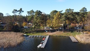 A dock with boats, a small pier, and a forested area with houses in the background.