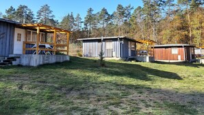 A campground with several wooden cabins, a covered picnic area, and a small shed.