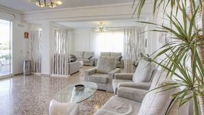 A spacious living room with a high ceiling, two sofas, a coffee table, and a large plant. - Roquetes Rooms - Formentera Break (Formentera)