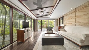 Un salon spacieux doté d’un grand téléviseur, de sièges confortables et offrant une vue sur l’extérieur.