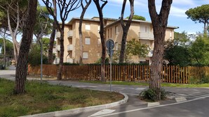 Un edificio residencial con varios balcones, rodeado de árboles y una cerca de madera.