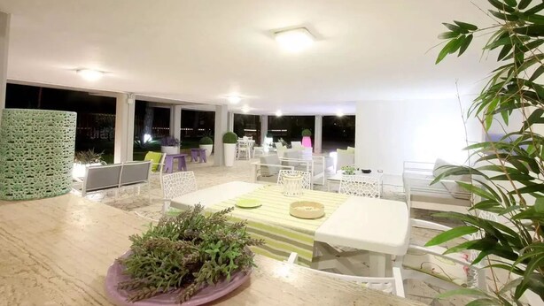Un área de comedor al aire libre con una mesa y sillas, rodeada de amplias ventanas y vistas al cielo nocturno.