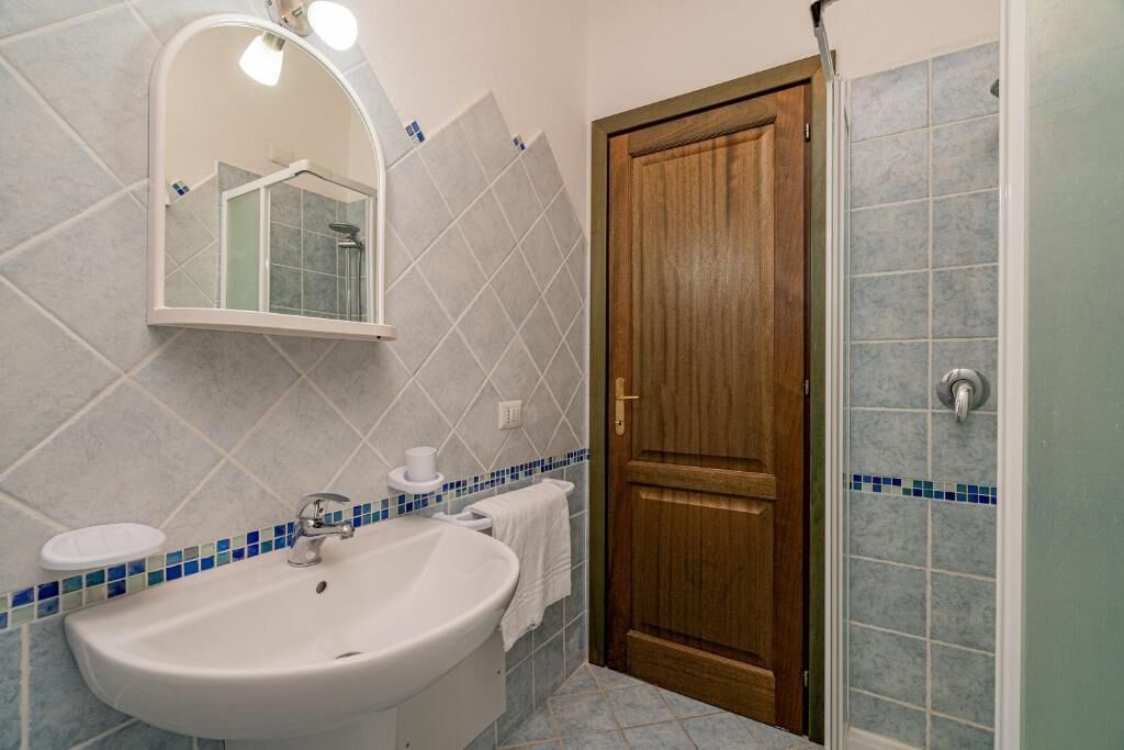 Baño con lavamanos, espejo y ducha.