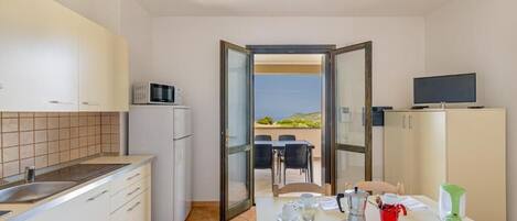Una cocina moderna con comedor, televisor y vistas al exterior.