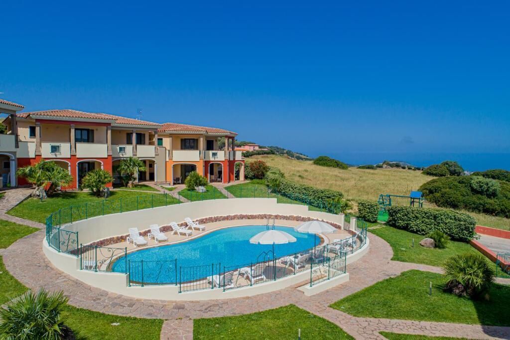 Un hotel con piscina, sillas de descanso al aire libre y vista al océano.