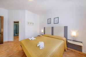 Una camera d'albergo con un letto, un comodino, uno specchio e una porta che dà su un bagno.