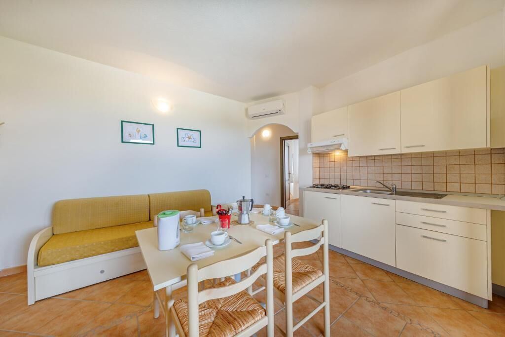 Cocina compacta con mesa, sillas, sof á y salpicadero de azulejos.
