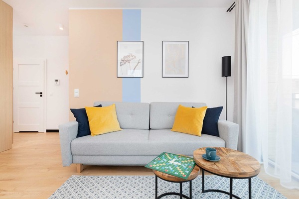 A bright living area featuring a cozy gray sofa, yellow cushions, a coffee table, and modern decor.