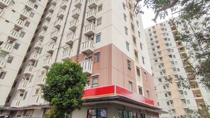 A high-rise residential building with multiple balconies and a central red and white structure. - Lily Room at Apartment Cibubur Village (Depok)