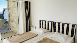 A bedroom with a bed, two pillows, and a beige blanket. - HORTENSIAS - Holiday apartment with sea view, facing the beach - T6 (Carnac)