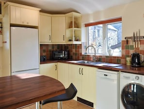 Une cuisine compacte équipée d’un réfrigérateur, d’un four à micro-ondes, d’un évier et d’un lave-linge.