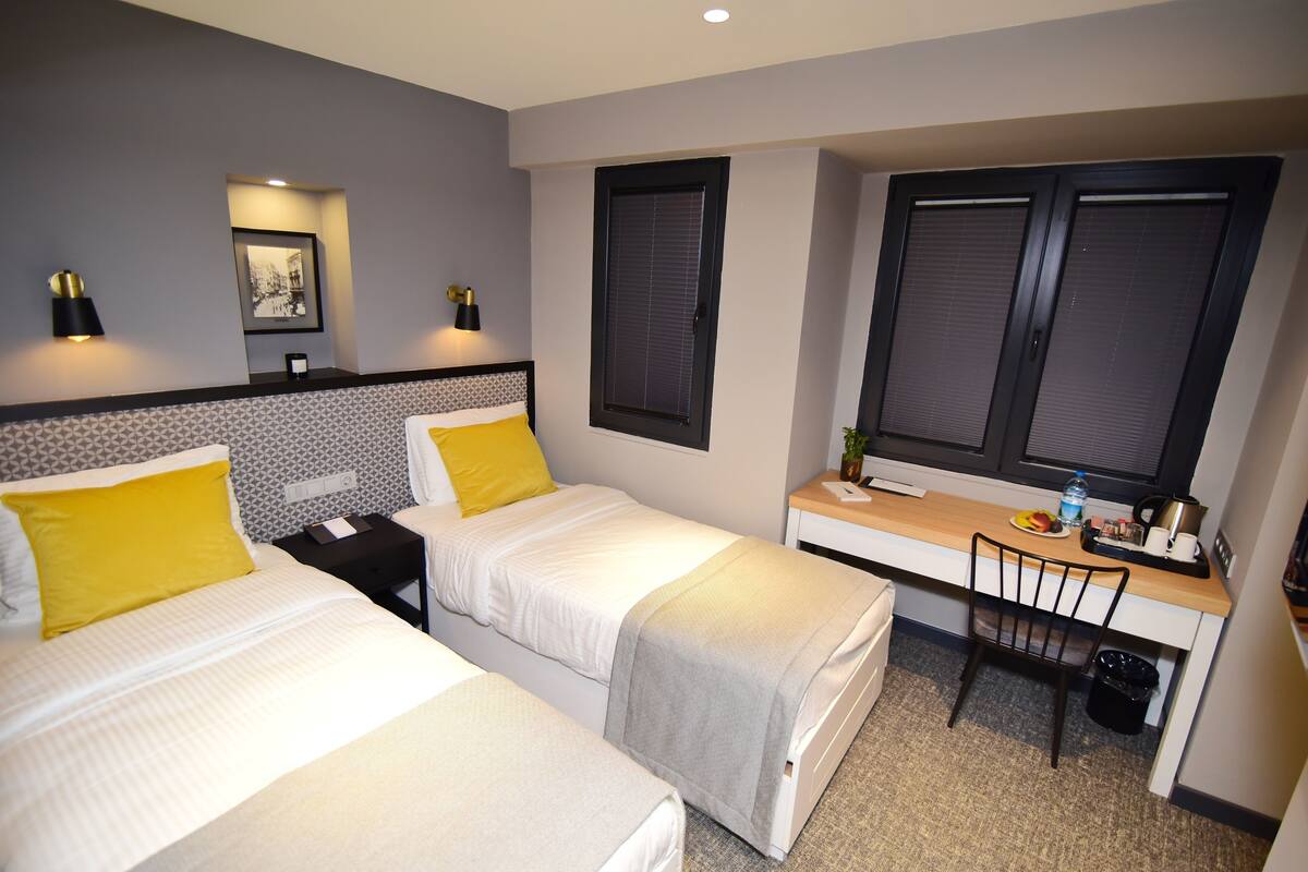 A hotel room with two beds, a desk, and a chair.
