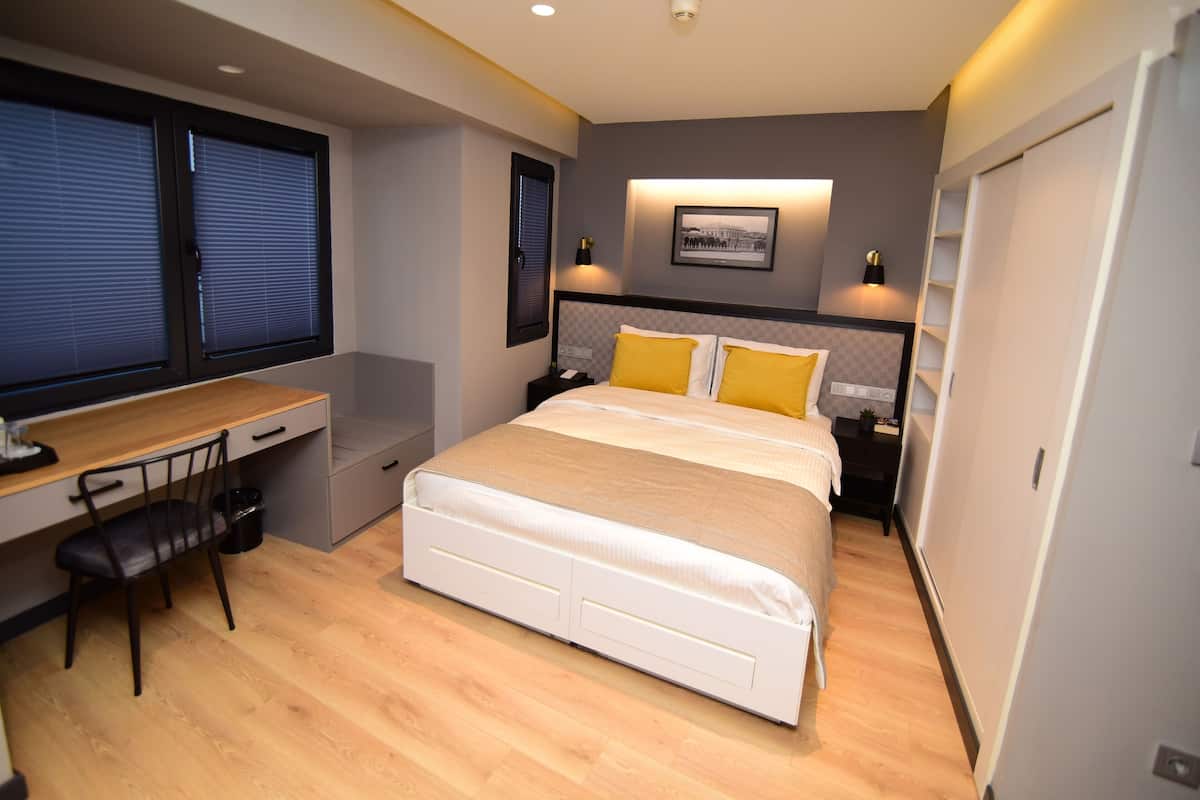 A bedroom with a bed, desk, chair, and a nightstand.