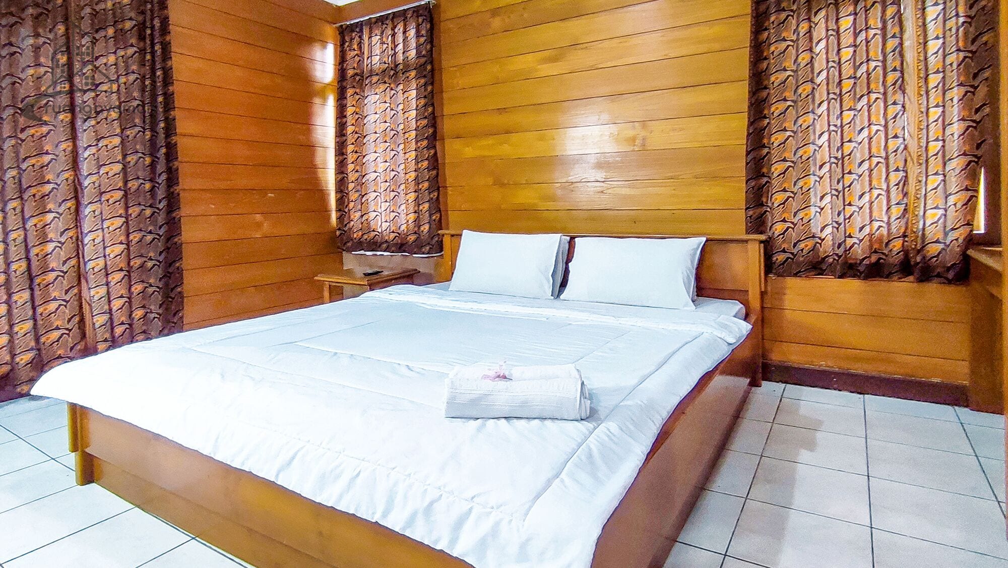 A room with a wooden bed, white bedding, and patterned curtains.