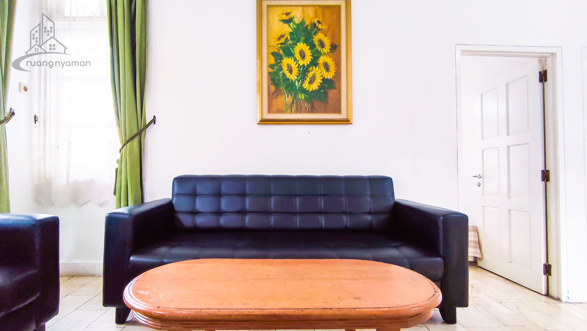 A living room with a dark blue sofa, a round wooden coffee table, and a framed painting of sunflowers on the wall.